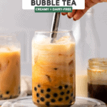 hand mixing glass of bubble tea with metal straw