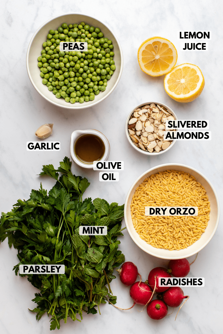 ingredients for orzo salad in small white bowls on marble countertop