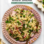 Orzo salad on pink plate with gold fork on marble background