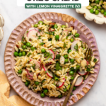 Orzo salad on pink plate with gold fork on marble background