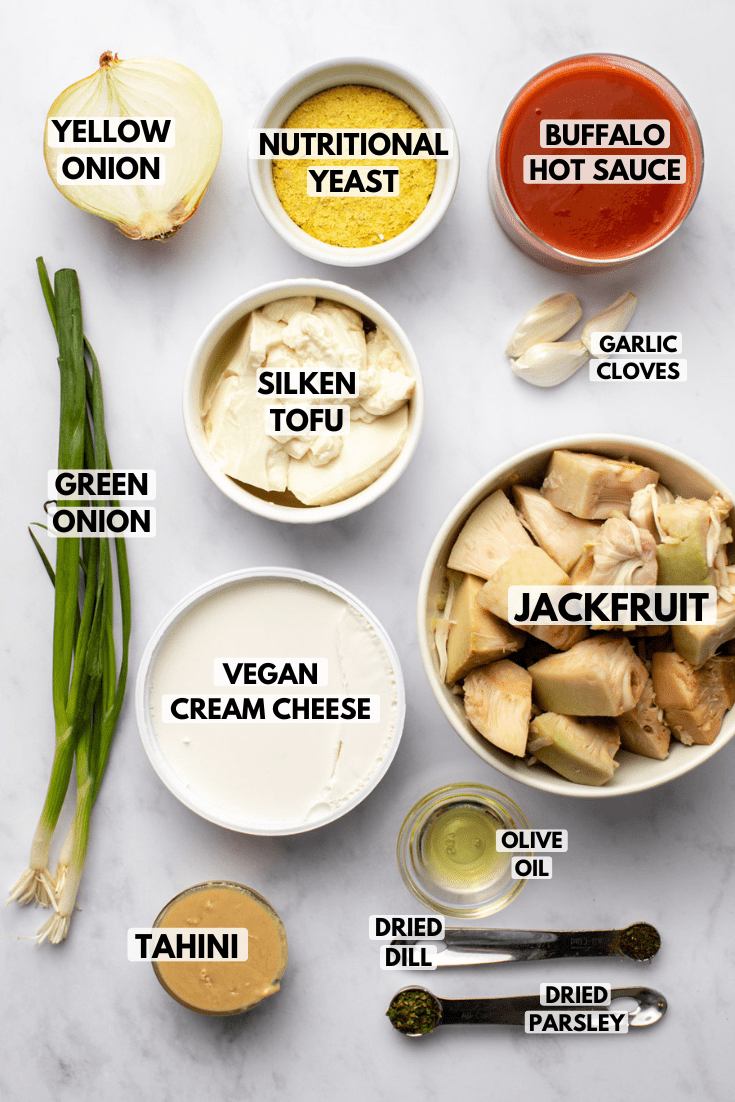 ingredients for the vegan buffalo chicken dip laid out on a marble kitchen countertop served in white bowls in various sizes