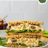 vegan chickpea salad sandwich sliced in half and stacked on white plate