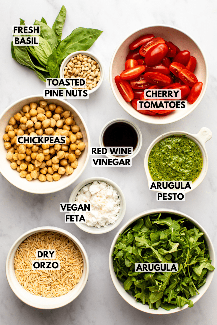 ingredients for pesto orzo salad laid out on a marble kitchen countertop